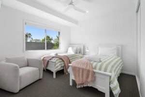 a bedroom with two beds and a couch and a window at 1 Seaspray Avenue in Coolum Beach