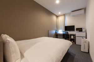 a bedroom with a bed and a desk with a computer at HOTEL R9 The Yard Hanazonointer in Imaichi
