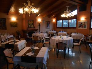 a restaurant with white tables and chairs and chandeliers at Hotel La Maddalena in Quattro Castella
