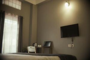 a bedroom with a bed with a flat screen tv on the wall at HO6 Homestay in Guwahati
