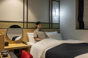 a man sitting on a bed in a hotel room at Mitasuya Ryokan Hotel by Anook Gwangju in Gwangju