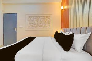 a bed with black and white pillows in a room at Super Hotel O Sahastradara Road Dehradun Formerly Kriswa Home in Dehradun