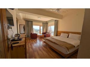 a bedroom with a bed and a desk and windows at Overland Heights - Near Leh Airport in Leh