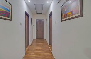 a hallway with white walls and wooden floors and paintings on the walls at Collection O NIT Srinagar Formerly Main Street Inn in Srinagar