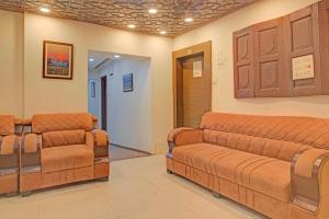 a waiting room with brown leather couches and chairs at Collection O NIT Srinagar Formerly Main Street Inn in Srinagar