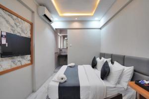 a bedroom with a bed and a tv on a wall at Hotel Palmera Inn in Pune