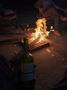 a person holding a bottle of wine next to a fire at Ikamba Residence in Rwamagana