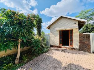 a house with a tree and a brick driveway at Stylish One Bedroom Garden Suite in Polokwane
