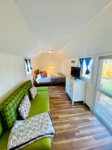 a living room with a green couch and a bedroom at Waldschenke Stendenitz Übernachten im Wald am See in Neuruppin