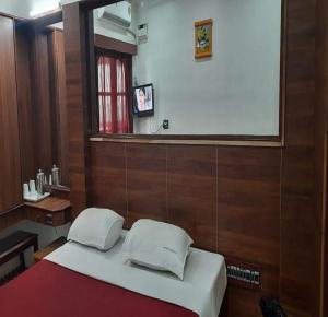 a bedroom with a bed with a mirror and a window at Ajantha Beach Guest House in Pondicherry +8 photos