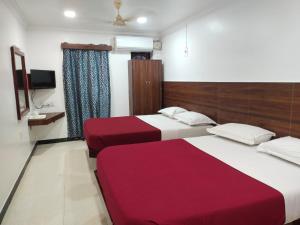 a hotel room with two beds and a tv at Ajantha Beach Guest House in Pondicherry