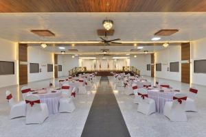 a banquet hall with white tables and white chairs at Ginger Kheda, Ahmedabad in Kheda +37 photos