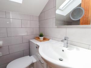 a bathroom with a sink and a toilet and a mirror at Kiloran in Rhosneigr +16 photos