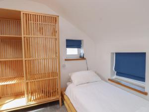 a small bedroom with a bed and a window at Kiloran in Rhosneigr