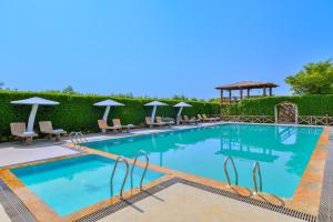 a pool at a resort with chairs and umbrellas at Ginger Kheda, Ahmedabad in Kheda