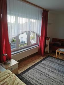 a bedroom with a large window with red curtains at Schöne Ferienwohnung Wetzlar in Wetzlar
