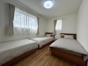 a bedroom with two beds and a window at 新築江の電腰越駅前徒歩1分鎌倉江の島観光に最適鎌倉腰越駅前ｂ棟 in Kamakura