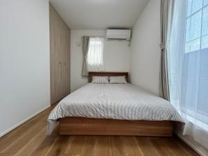 a small bedroom with a bed and a window at 新築江の電腰越駅前徒歩1分鎌倉江の島観光に最適鎌倉腰越駅前ｂ棟 in Kamakura