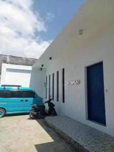 a motorcycle parked next to a building with a van at J and M Pension House in Dipolog