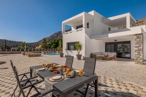 a villa with a table and chairs on a patio at Luxury Villa Amani Retreat in Lindos