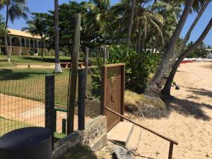 a gate on a beach with palm trees and a building at Solar dos Arcos in Praia do Forte