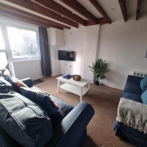 a living room with a blue couch and a table at Cilan in Llangian +3 photos
