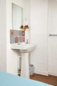 a white bathroom with a sink and a mirror at Cilan in Llangian