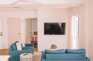 a living room with two blue chairs and a tv at Yamba Beach Motel in Yamba
