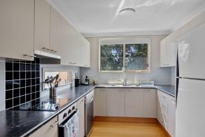 a white kitchen with white cabinets and a window at Seabreeze Cottage in Manyana