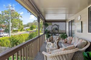 a porch with wicker chairs and a table at Seabreeze Cottage in Manyana