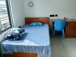 a bedroom with a bed and a desk and a chair at The Palindrome in Guwahati