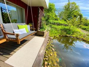 a porch with a swing next to a body of water at Gästehaus Natur in Vöhl