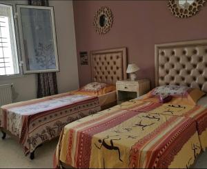 a bedroom with two beds and a table with a lamp at Confort house-au bord de la mer in Nabeul