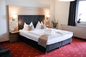 a hotel room with a large bed with white pillows at Hotel Am Greiner in Rust +28 photos