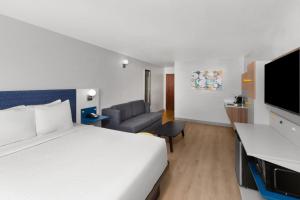 a hotel room with a bed and a couch at Microtel Inn and Suites Baton Rouge Airport in Baton Rouge