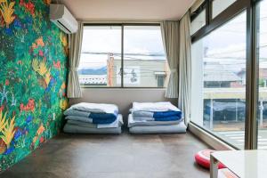 two beds in a room with a large window at ゲストハウスシナノスイー Guest House Shinano Swee in Omachi +120 photos