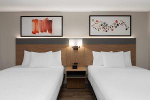 two beds in a hotel room with white sheets at Hawthorn Extended Stay by Wyndham Jackson in Jackson
