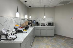 a kitchen with white cabinets and a counter with fruits on it at Ramada by Wyndham Cobleskill in Cobleskill