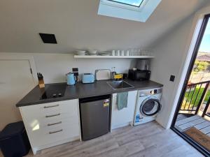 a kitchen with a sink and a washing machine at Great Warm Studio Unit in Queenstown Airport +3 photos