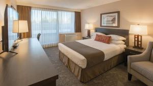 a hotel room with a large bed and a chair at The Embassy Inn in Victoria