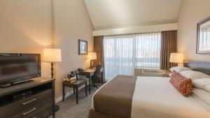 a hotel room with a bed and a flat screen tv at The Embassy Inn in Victoria +28 photos