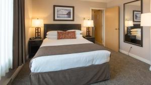 a large bed in a hotel room with two lamps at The Embassy Inn in Victoria