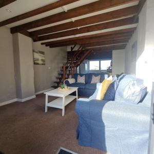 a living room with a blue couch and a table at Fadrun Cottage in Llangian