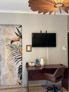 a home office with a desk and a flat screen tv at The Chalant in Tzaneen