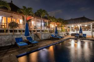 a pool with chairs and umbrellas next to a building at Tatak Bunut Villa Ceningan in Nusa Lembongan