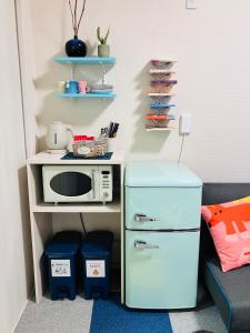 a small kitchen with a microwave and a refrigerator at 旅の宿 もはち Private Guesthouse MOHACHI in Tsuruoka