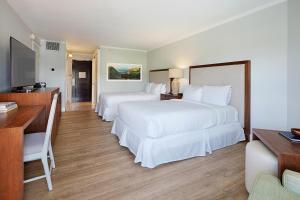a hotel room with two beds and a desk at Kauai Beach Resort in Lihue +4 photos