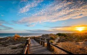 a wooden boardwalk to the beach at sunset at PISO CENTRICO EN PUNTA UMBRIA in Punta Umbría