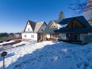 a house in the snow with a pile of snow at Apartmán Dvojka in Benecko