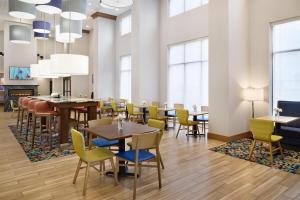 a dining room with tables and chairs and windows at Hampton Inn & Suites Syracuse North Airport Area in North Syracuse